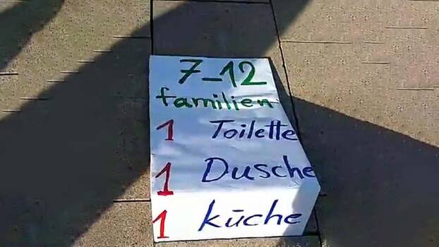 Ein selbstgeschriebenes Plakat macht auf die Situation der Geflüchteten im Erstaufnahmeeinrichtung im Bargkoppelstieg in Hamburg aufmerksam. 7-12 Familien, eine Toilette, eine Dusche, eine Küche steht auf dem Plakat. 